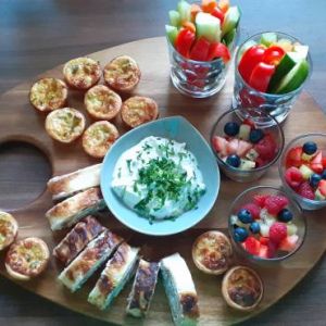 Fingerfoodplatte mit Lachsröllchen, Gemüsesticks, Mini Quiche und Obstsalat